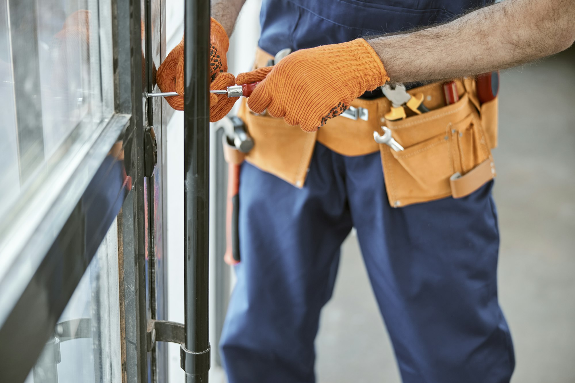 Male worker in work gloves repairing door in house